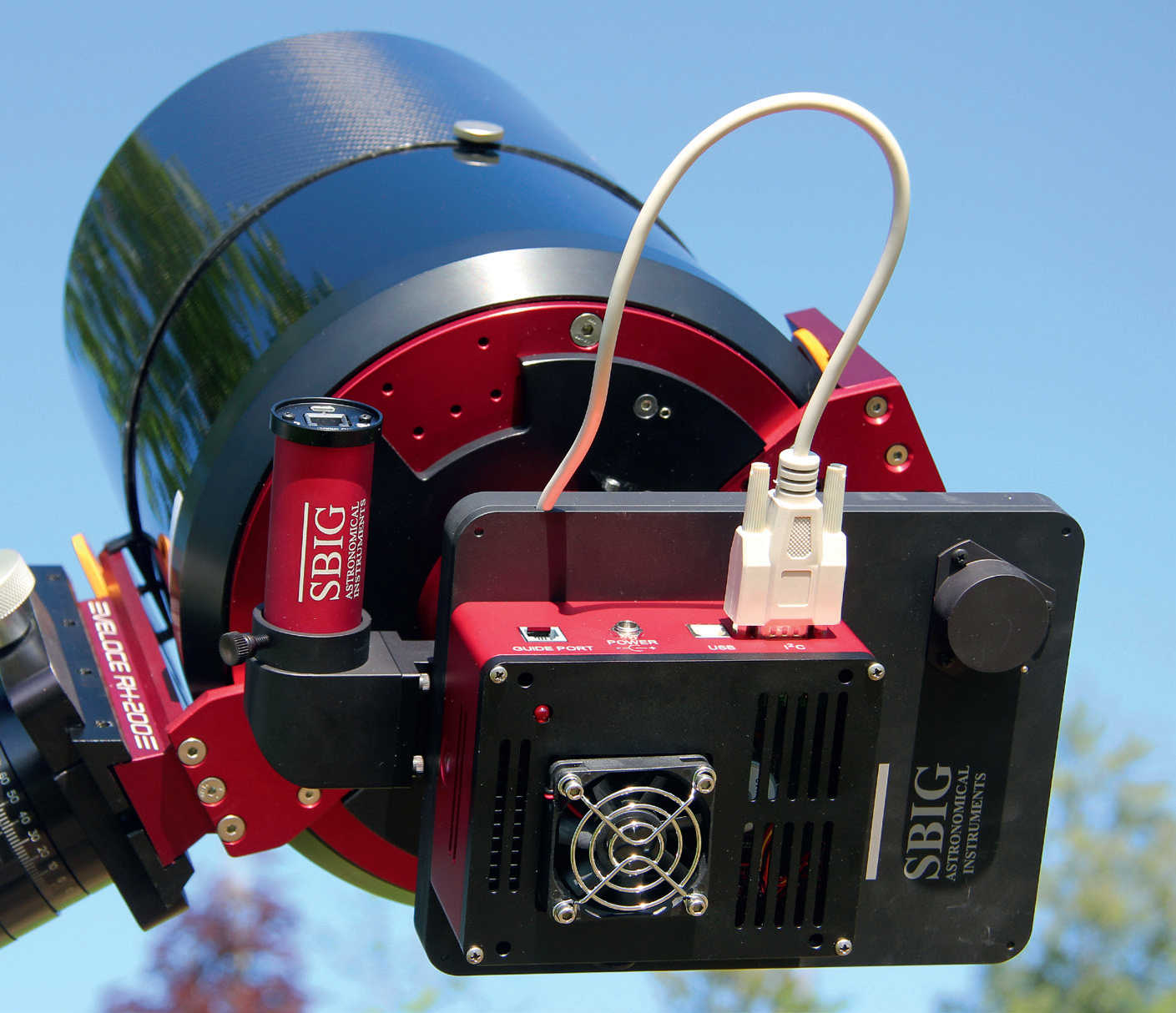 Uma câmara CCD refrigerada num astrógrafo: entre o telescópio e a câmara (corpo vermelho e preto) pode ver-se a roda de filtros (também preta) e, junto a ela, uma câmara de seguimento redonda (vermelha) que está conectada ao percurso de feixes do raio do telescópio através de um guia fora do eixo. U. Dittler