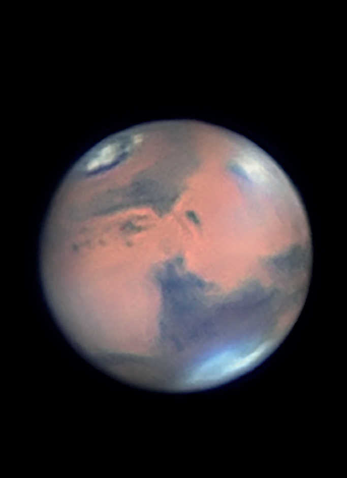 Imagem do planeta Marte. A fotografia mostra claramente nuvens junto ao grande vulcão-escudo Elysium Mons. A calota polar norte acentuadamente derretida é igualmente muito marcante. Mario Weigand